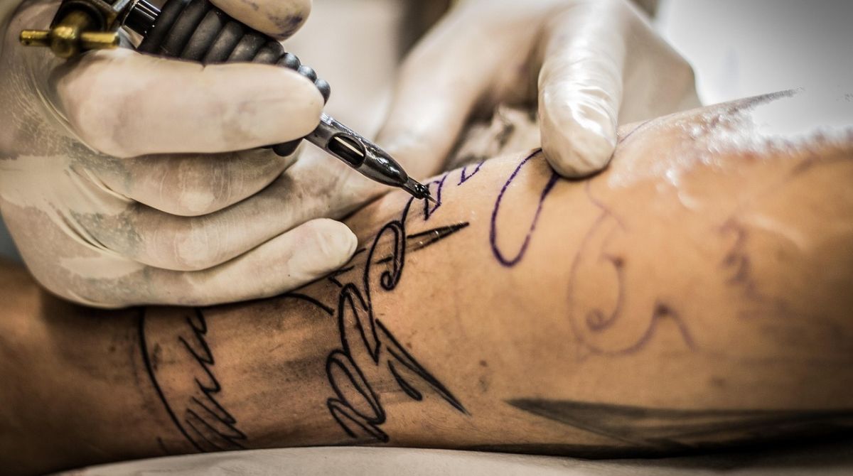 Detalhe de braço sendo tatuado