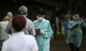 Enfermeira faz triagem em frente a uma unidade de saúde