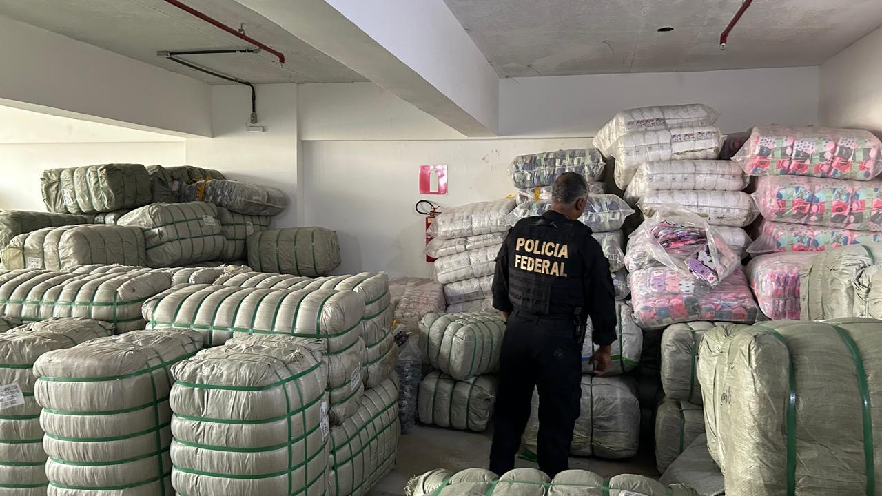 Um agente da Polícia Federal parado em frente à mercadorias contrabandeadas.