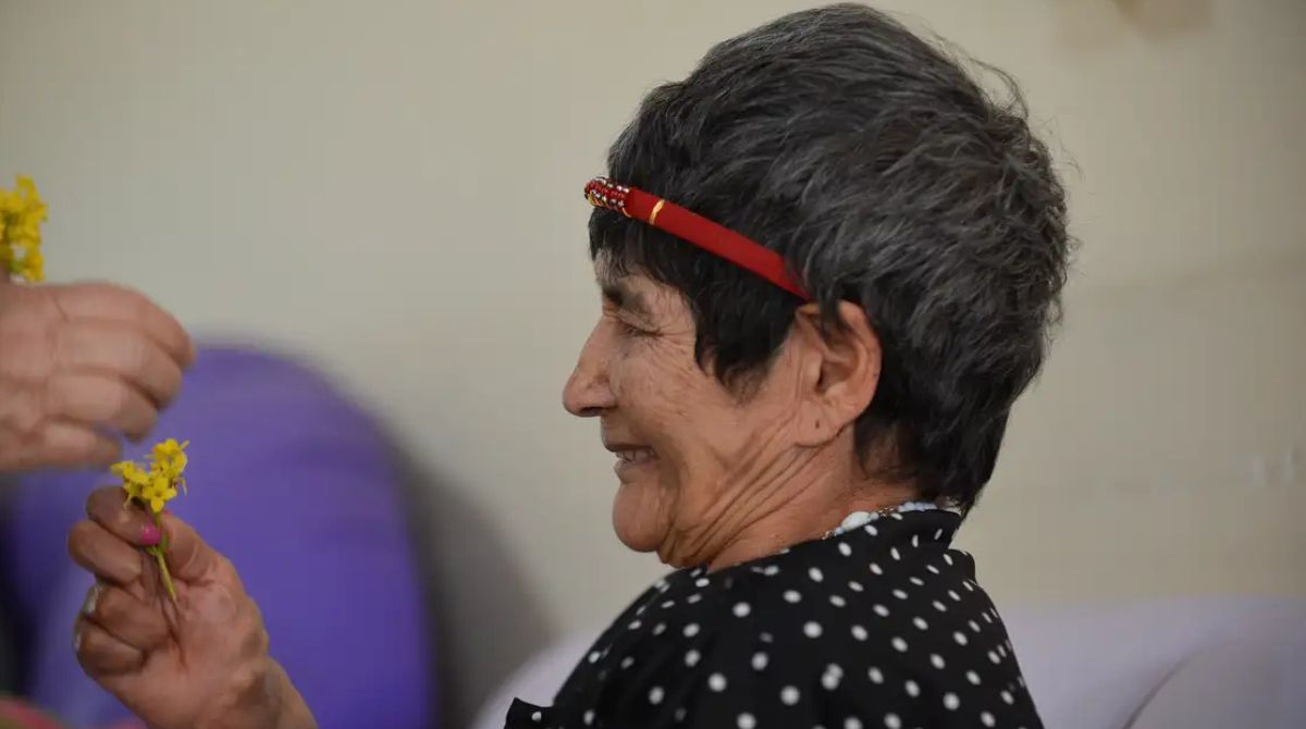 Mulher idosa recebendo flor