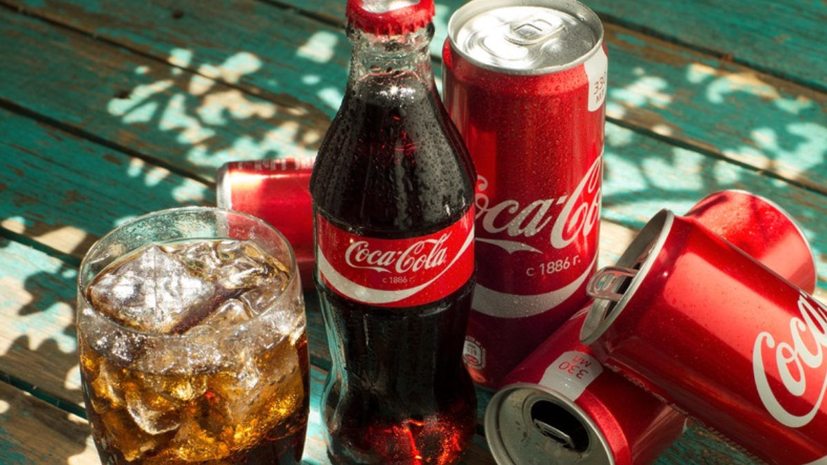foto mostra copo, garrafa e latas de coca-cola
