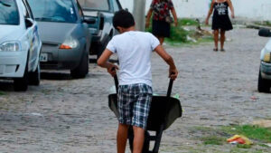 foto mostra criança carregando carrinho de mão